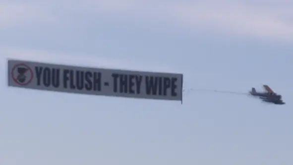 یک Dodo که بنر «You Flush - They Wipe» را یدک میکشد.